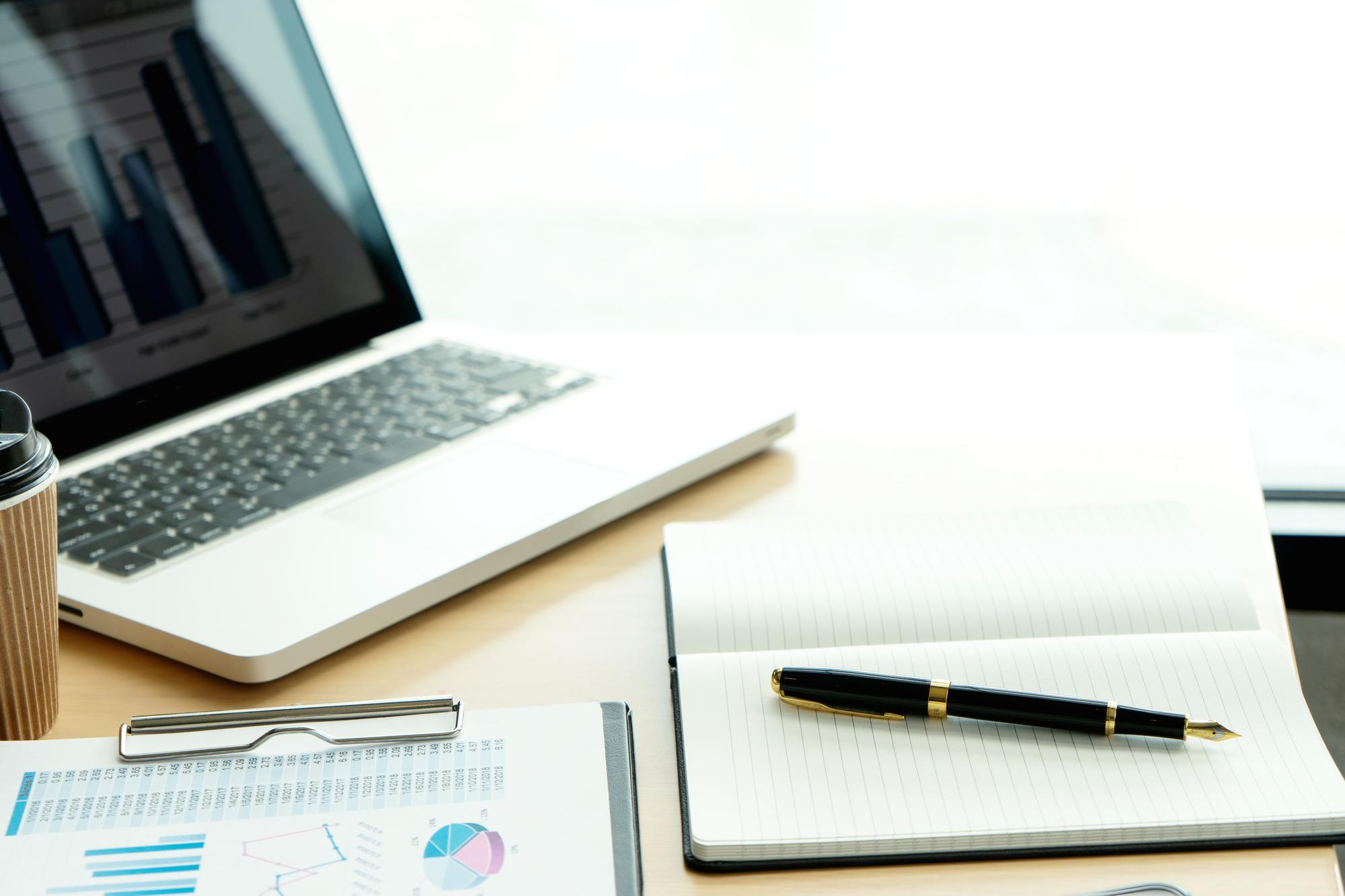 Editorial workspace mit Laptop und Finanzunterlagen